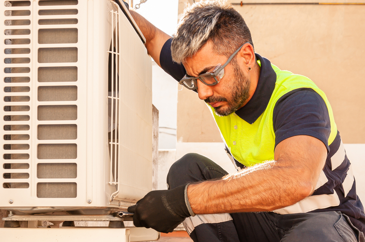 Male technician installing outdoor unit of air conditioner